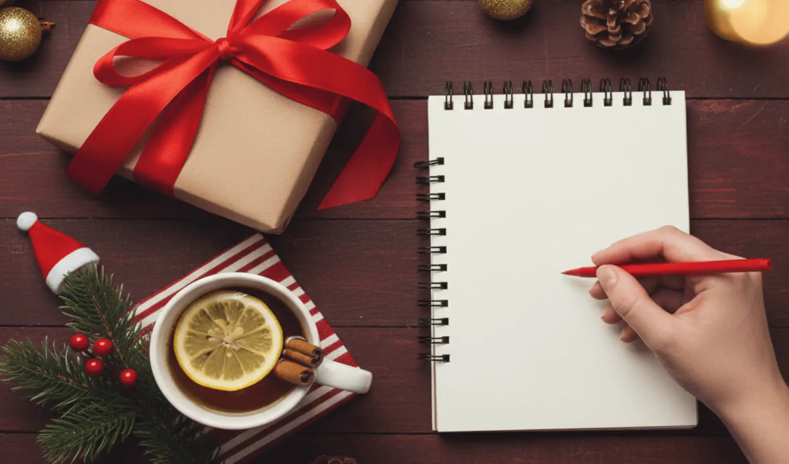 Christmas gifts with red ribbons, lemon tea, and an empty notebook for planning gifts